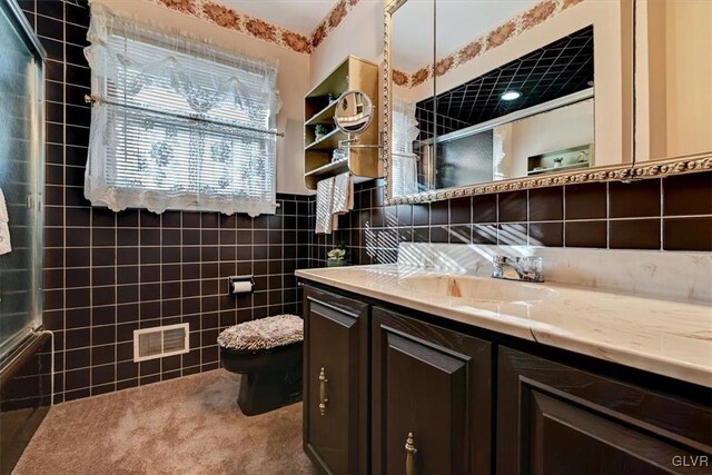 bathroom featuring vanity, a shower with shower door, toilet, and tile walls