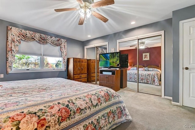 bedroom featuring light carpet, two closets, and ceiling fan