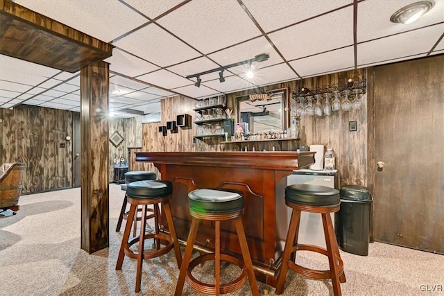 bar featuring wood walls, a drop ceiling, and light colored carpet