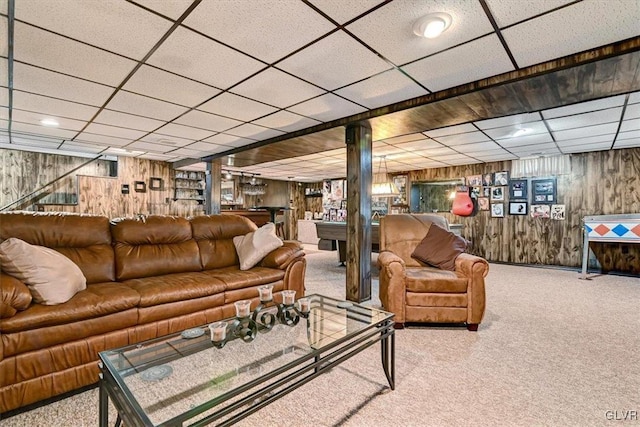 carpeted living room featuring wood walls and a paneled ceiling