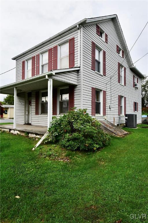 rear view of house with covered porch, a lawn, and central AC unit