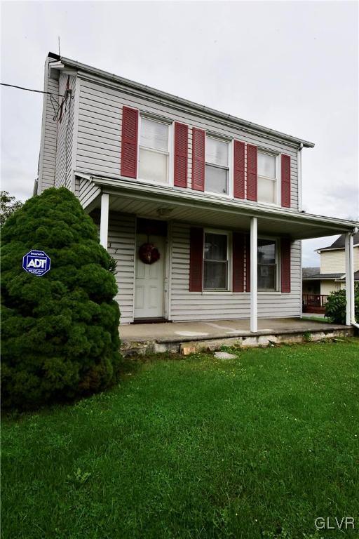 view of front of home with covered porch and a front lawn