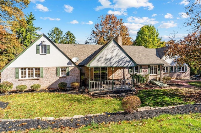 tudor-style house with a front yard and covered porch