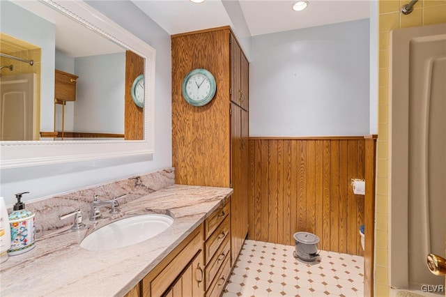 bathroom featuring vanity, wooden walls, and a shower