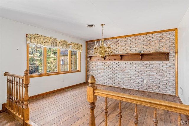 mudroom with brick wall, hardwood / wood-style flooring, and an inviting chandelier