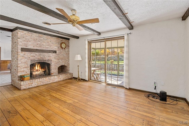 unfurnished living room featuring beam ceiling, a textured ceiling, wood-type flooring, and a fireplace