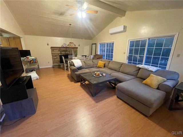 living room featuring a wall unit AC, lofted ceiling with beams, a fireplace, light hardwood / wood-style floors, and ceiling fan