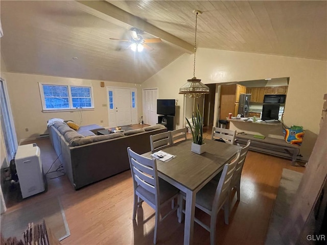 dining room with light hardwood / wood-style flooring, vaulted ceiling with beams, and ceiling fan with notable chandelier