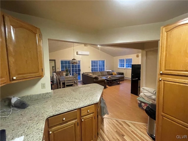 kitchen featuring lofted ceiling, a wall mounted AC, light stone countertops, light wood-type flooring, and decorative light fixtures