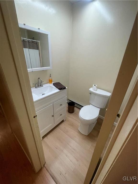 bathroom featuring wood-type flooring, toilet, vanity, baseboard heating, and a shower with shower curtain