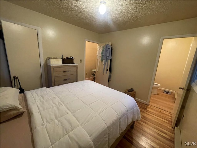 bedroom featuring light hardwood / wood-style floors, a textured ceiling, and ensuite bathroom