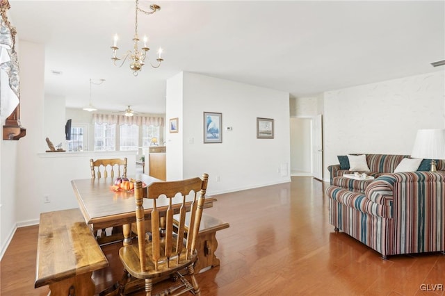 dining space featuring ceiling fan with notable chandelier and hardwood / wood-style flooring