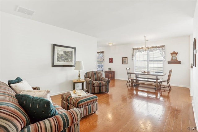 living room with light wood-type flooring and a chandelier