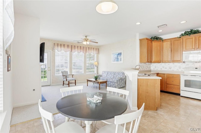 kitchen with ceiling fan, backsplash, kitchen peninsula, sink, and white appliances