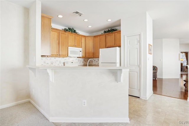 kitchen featuring a kitchen breakfast bar, sink, kitchen peninsula, and white appliances