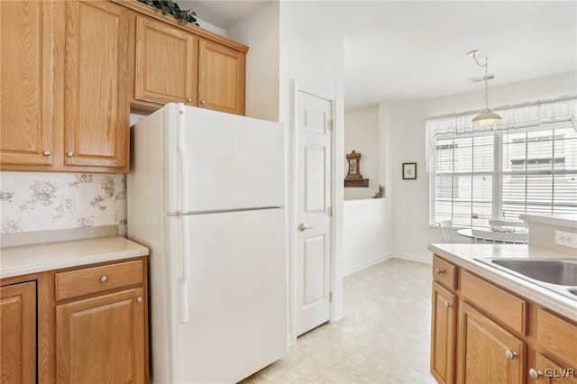 kitchen featuring white refrigerator, pendant lighting, and sink