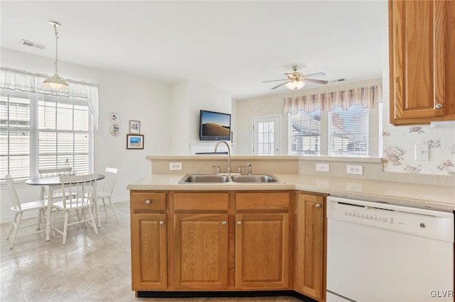 kitchen featuring ceiling fan, a healthy amount of sunlight, white dishwasher, hanging light fixtures, and sink