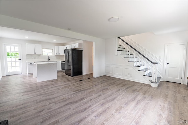 unfurnished living room with sink and light hardwood / wood-style floors