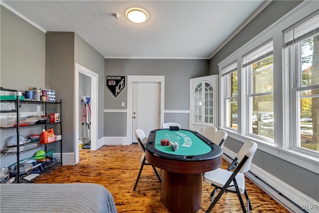 rec room with wood-type flooring, ornamental molding, and a wealth of natural light