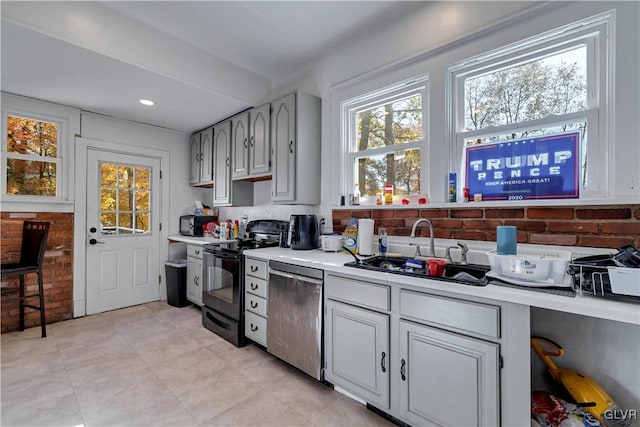 kitchen with black electric range oven, stainless steel dishwasher, sink, and gray cabinetry