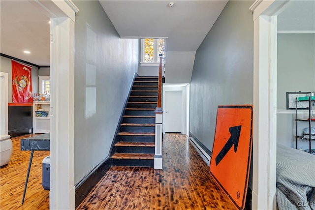 stairs with ornamental molding, a baseboard heating unit, and hardwood / wood-style flooring