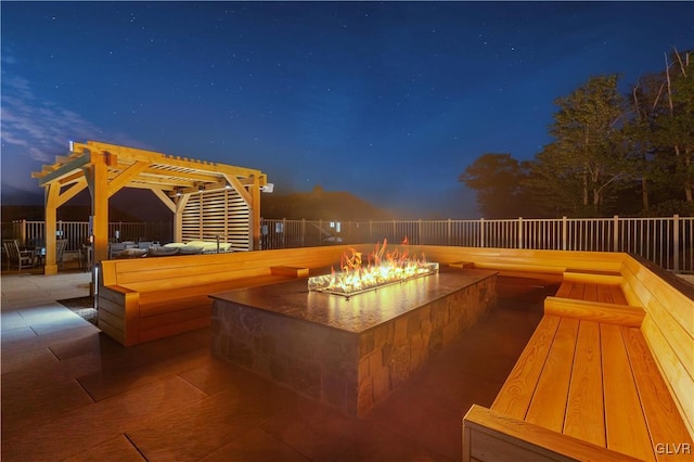 patio terrace at dusk featuring a pergola and a fire pit