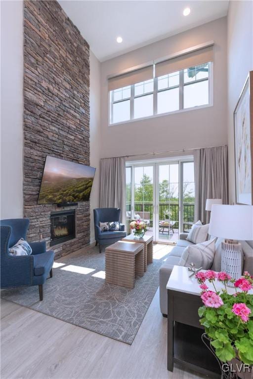 living room with hardwood / wood-style flooring, a high ceiling, and a fireplace