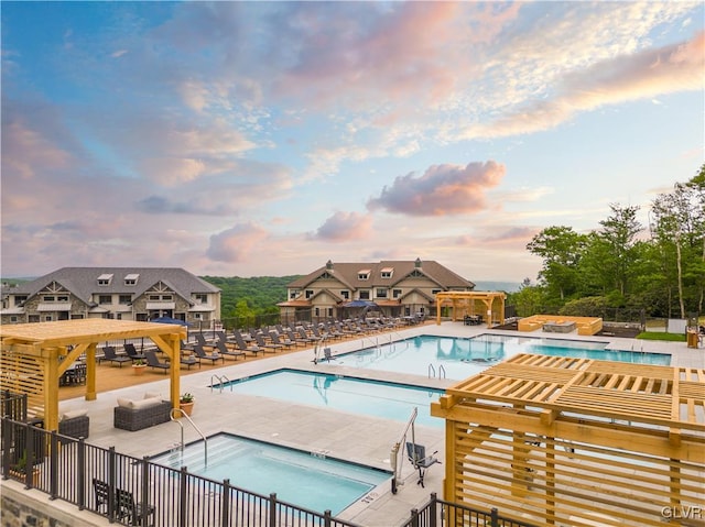 pool at dusk featuring a patio and a hot tub