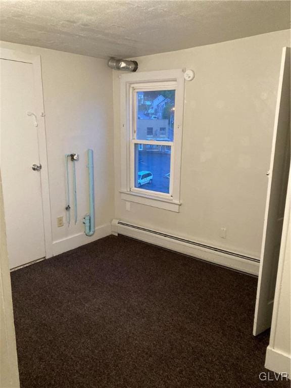 unfurnished room with a baseboard heating unit, a textured ceiling, and dark colored carpet