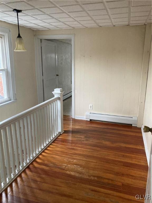 hallway featuring a drop ceiling, baseboard heating, and dark hardwood / wood-style flooring