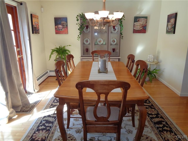 dining room with a notable chandelier, a baseboard radiator, and light wood-type flooring