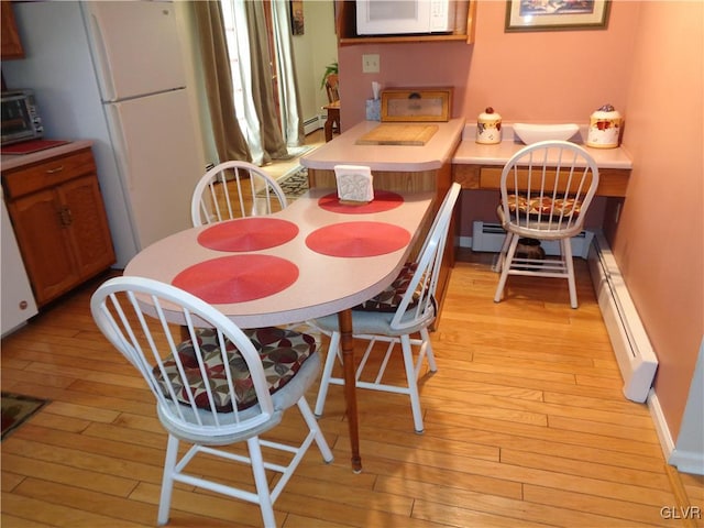 dining space with baseboard heating and light wood-type flooring