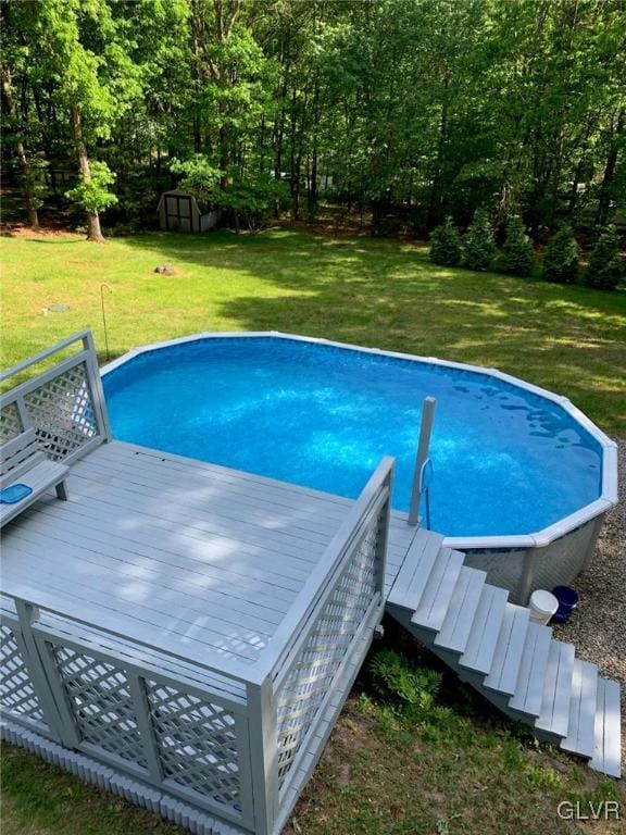 view of pool featuring a shed, a lawn, and a wooden deck