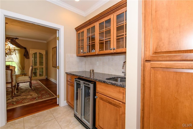 kitchen featuring beverage cooler, crown molding, sink, light tile patterned floors, and dark stone countertops