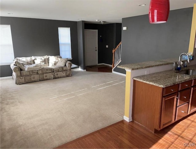 interior space featuring light stone countertops, carpet, sink, and kitchen peninsula