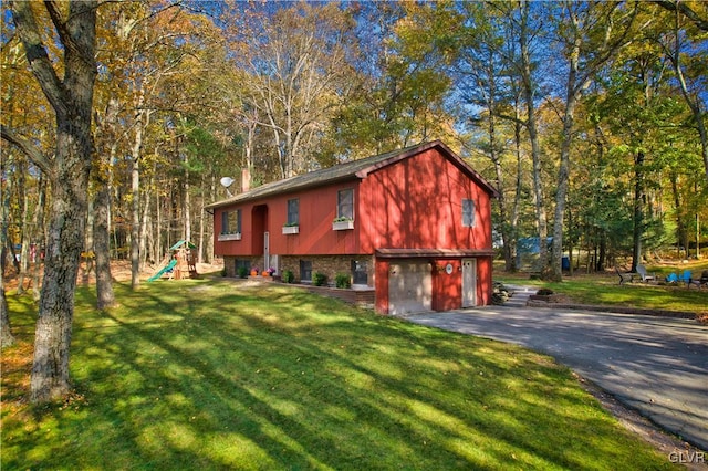 view of front of property featuring a front yard, a garage, and a playground