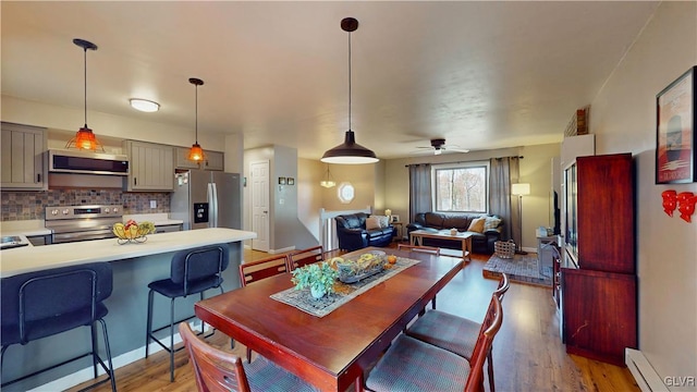 dining room featuring a baseboard heating unit, light wood-type flooring, and ceiling fan