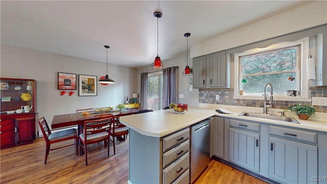 kitchen featuring kitchen peninsula, hanging light fixtures, stainless steel dishwasher, plenty of natural light, and sink