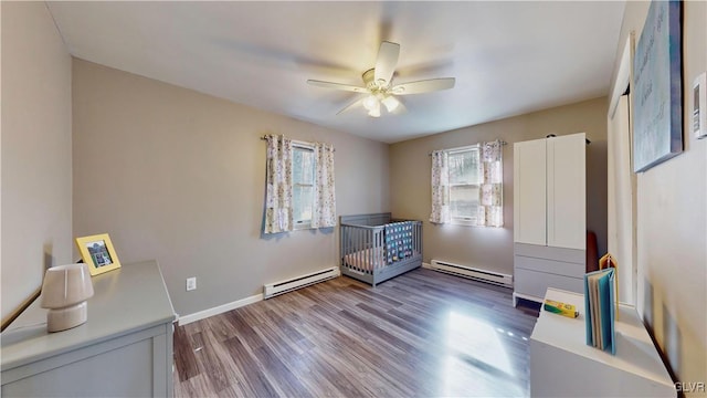 interior space featuring ceiling fan, wood-type flooring, and a baseboard heating unit