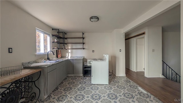 kitchen with light stone counters, a barn door, light wood-type flooring, gray cabinets, and sink