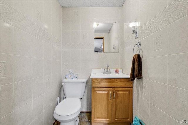 bathroom with vanity, tile walls, and toilet