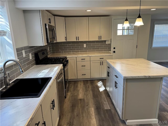 kitchen with decorative backsplash, a kitchen island, dark wood-type flooring, sink, and appliances with stainless steel finishes