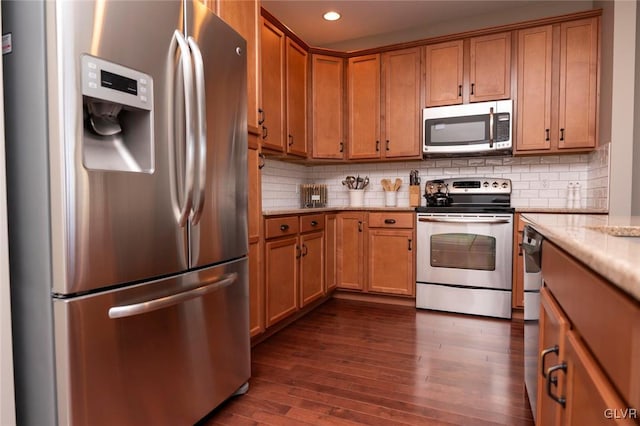 kitchen featuring dark hardwood / wood-style floors, light stone countertops, appliances with stainless steel finishes, and tasteful backsplash