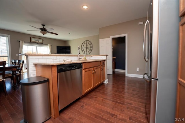 kitchen featuring sink, ceiling fan, an island with sink, appliances with stainless steel finishes, and dark hardwood / wood-style flooring