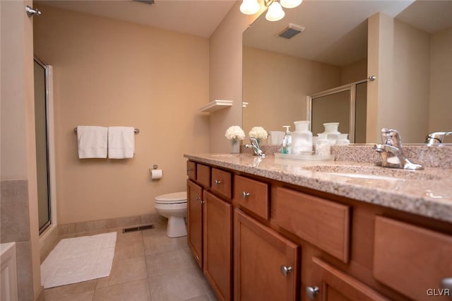 bathroom with tile patterned flooring, vanity, toilet, and a shower with door