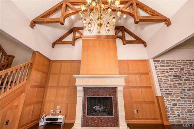 living room featuring a notable chandelier, a high end fireplace, wooden walls, and high vaulted ceiling