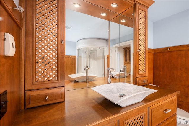 bathroom featuring vanity, toilet, wood walls, and an enclosed shower