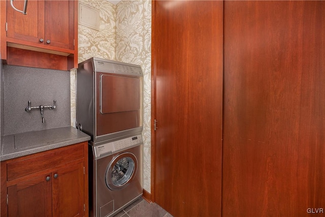 washroom featuring cabinets, stacked washer / drying machine, and tile patterned flooring