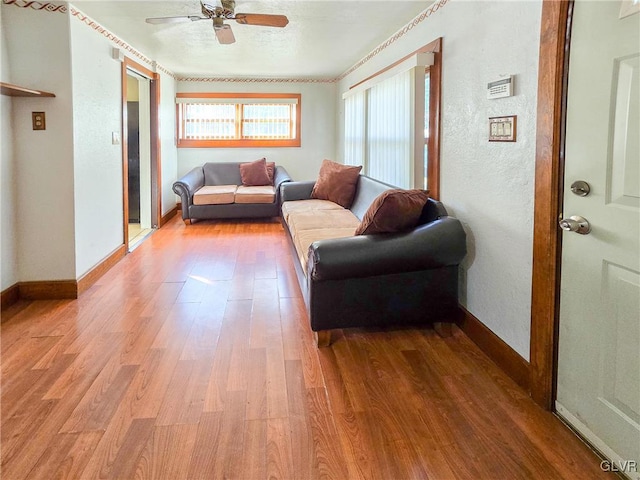 living room with crown molding, wood-type flooring, and ceiling fan