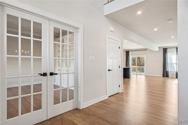 hall with light hardwood / wood-style floors and french doors